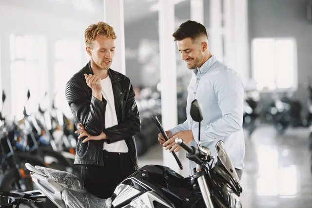 Two men engaged in conversation over a motorcycle in a showroom. Modern and vibrant setting. Native advertising for product education